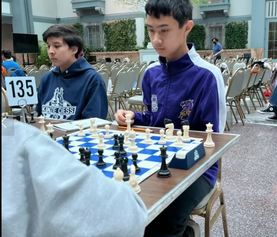 Two players seated behind a board marker reading 135.