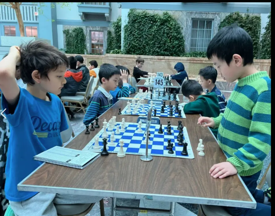 Players deep in their games at boards numbered 143 and 145.